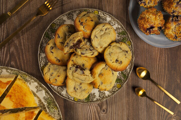 Chocolate chip cookies, muffins, cheesecake top view with beautiful crockery