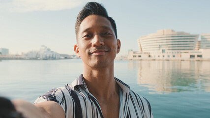 Close-up of young man standing on dock taking selfie with cell phone