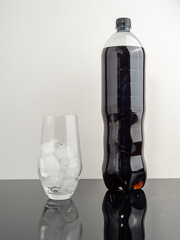 Bottle of cola and glass with ice. Close-up.