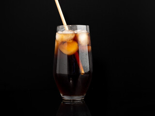 Glass of cola with ice on a black background. Close-up.
