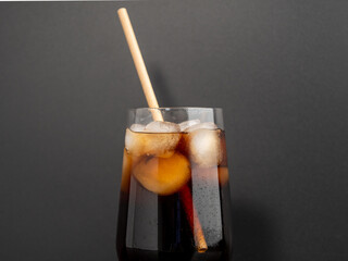 Glass of cola with ice on a black background. Close-up.