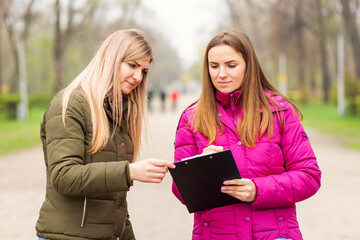 Opinion poll. A woman interviewing people, conducting survey standing outdoor