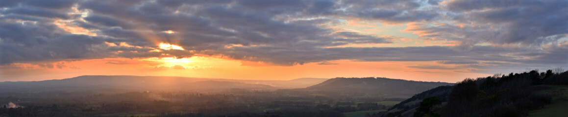 Sunset panoramic view from Colley Hill between Reigate and Dorking in Surrey, UK. Surrey Hills area of Outstanding Natural Beauty on the North Downs. Looking towards Leith Hill on the Greensand Ridge.