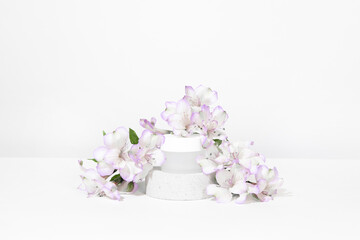 A mock up white jar of cream on a natural stone podium pedestal, on a white table, with plant,...
