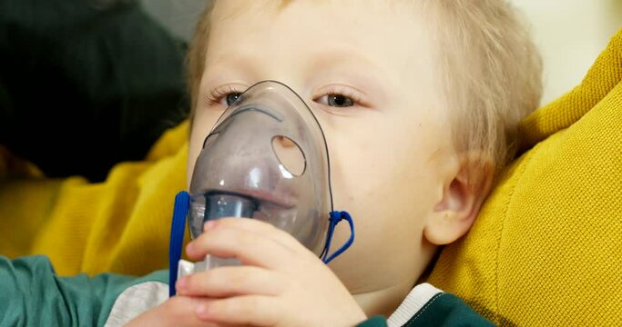 Portrait of a child with an inhaler respirator on his face, treating the respiratory tract of children with an inhaler spray