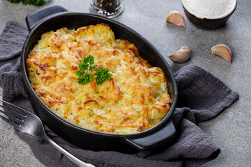 Potato casserole with cheese and parsley on stone background. French cuisine, top view