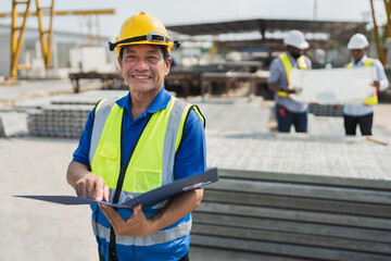 Portrait Asia senior engineer man holding document file with team working with paper work and precast cement factory background