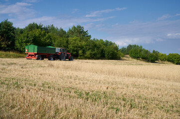 Fototapeta na wymiar Tractor with trailer in grain field