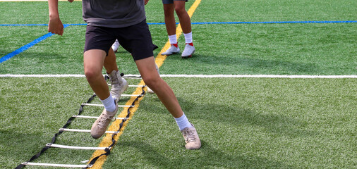 Football players running the ladder drill at summer preseason camp
