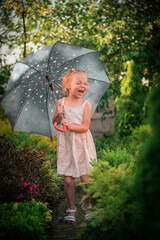 A girl with a gray umbrella jumps in the rain
