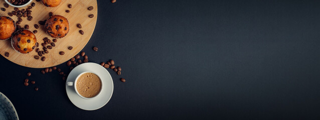 Desayuno con taza de café, muffins de chocolate, en madera, con granos de café, en fondo banner largo oscuro azul
