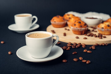 Dos tazas de café, desayuno con muffins de chocolate, en una bandeja de madera, granos de café en fondo azul oscuro