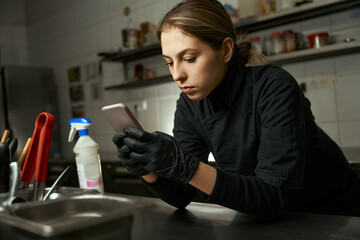 Female chef in overalls holds a phone in her hands