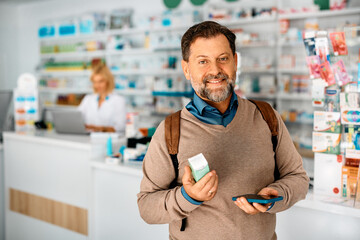 Happy man shopping in drugstore and looking at camera.