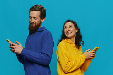 Woman and man cheerful couple with phones in their hands crooked smile cheerful, on blue background. The concept of real family relationships, talking on the phone, work online.