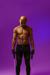 Fototapeta na wymiar Sporty man performs exercises with expander on studio background. Strength and motivation