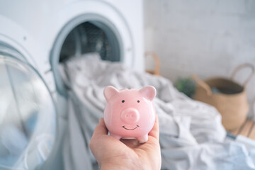 Energy and electricity crisis, money savings piggy bank. Reduce household bills expenses washing...