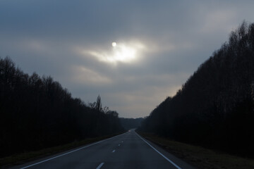 Lonely road at the dark nasty day, cold sun breaks through the clouds. Concept of anxiety