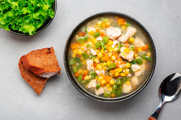 Hot vegetable soup with chicken, corn and green beans. Comfort food. Gray table background, top view