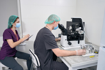 Man at a microscope carries out the fertilization of egg