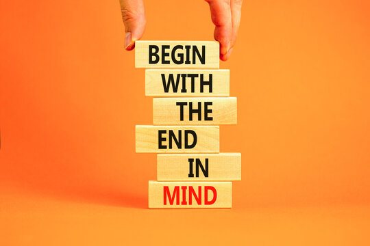 Begin in end of mind symbol. Concept words Begin with the end in mind on wooden blocks. Beautiful orange table orange background. Businessman hand. Business begin in end of mind concept. Copy space.