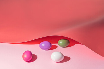 Colorful easter eggs under a pink paper cover. Minimal Easter holiday concept