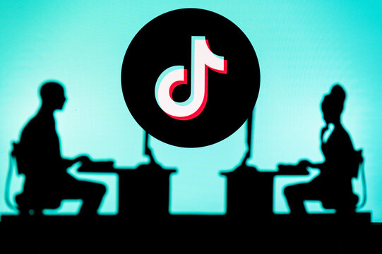 UK, LONDON. JANUARY 30, 2023: TikTok. Innovating the Future: Silhouette of Two Software Developers and the Company's Logo in the Background