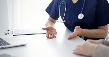 Doctor and patient discussing current health questions while sitting at the table in clinic, jast...