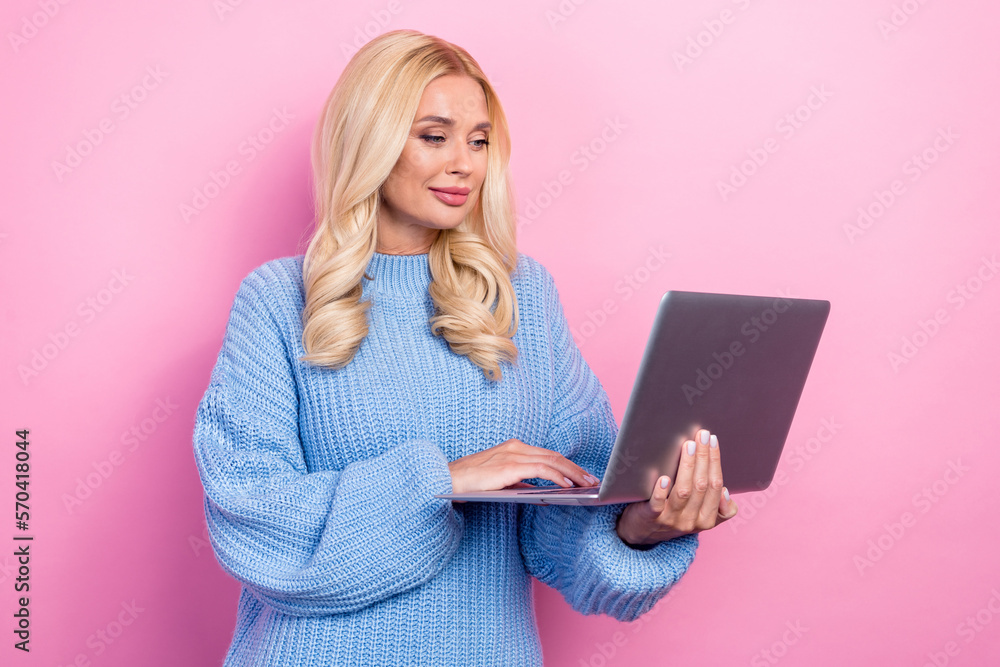 Poster Photo of concentrated positive woman curly hairstyle wear blue sweater hold laptop checking email isolated on pink color background