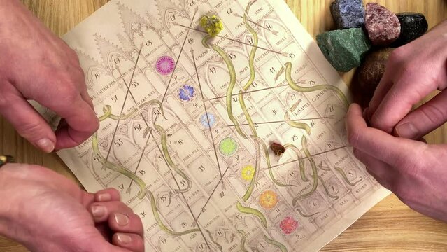 Table top view game board of Leela. Unrecognizable female male hands playing Indian ancient game indoors. Players getting insight into human consciousness, key to divine knowledge. Esoteric session