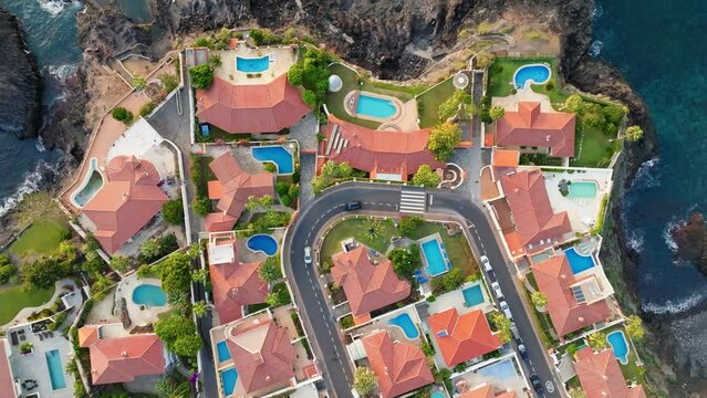 Gorgeous private villas with orange roofs and ocean views next to the beach. Aerial top down view of luxury oceanfront pool villas. Comfortable rest and privacy