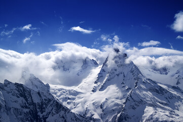 Fototapeta premium Snowy mountains in sunlight clouds