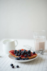 breakfast on a white table. free space for text. bun with jam, blueberries and cocoa