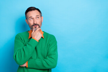 Photo of minded clever man arm touch chin look interested empty space isolated on blue color...