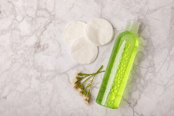 Micellar cleansing water and cotton pads on a marble background. Facial cleansing or makeup remover cosmetic bottle in bathroom. Skin care concepts. Cleansing the face of makeup and skin sebum.