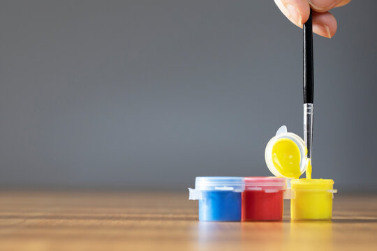 Artist Paint Brush With Colorful Paint On Wooden Table With Gray Background, Copy Space Blue, Red And Yellow