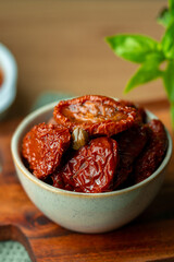 Bowl of sun dried tomatoes on wooden background.Dried tomato. Sun dried tomatoes. Infinite depth of field. Sun dried tomatoes with fresh herbs and spices. Slate background.Autumn seasonal pickled 