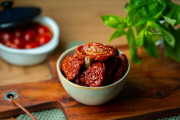 Bowl of sun dried tomatoes on wooden background.Dried tomato. Sun dried tomatoes. Infinite depth of field. Sun dried tomatoes with fresh herbs and spices. Slate background.Autumn seasonal pickled 