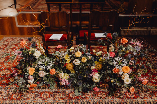 Grand bouquet de fleurs devant les chaises des futurs époux