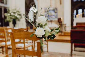 Les chaises de l'église décorées de fleurs pour la cérémonie 