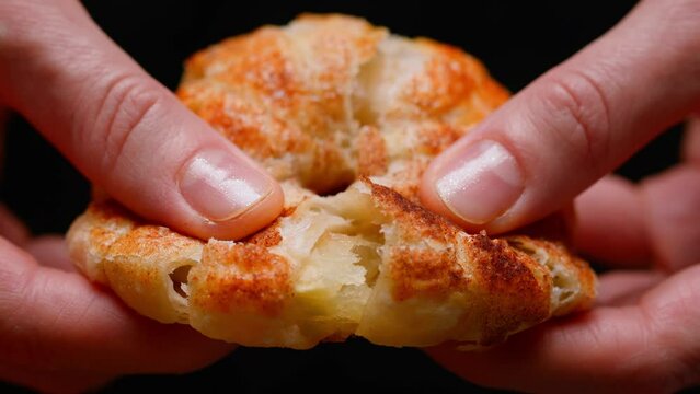 hands breaking pastries from puff pastry. close-up of baking on a black background. slow motion
