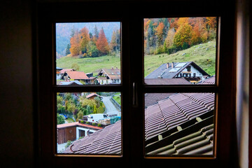 View from the window of the house to the Alps, trees and mountain slopes in autumn.