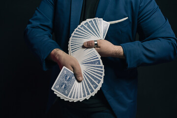 Close-up image of a young magician's hands in the dark showing a pair of linked decks of cards in the shape of an S or linked fans. Shows the back side of the deck.
