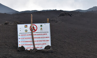 Information sign on Etna volcano "It is forbidden to exceed this limit", lava slag in the background, Sicily, Italy