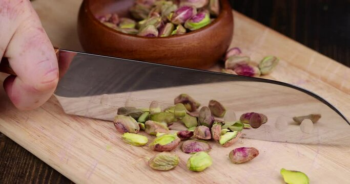 Green mature pistachios without shells during grinding, cutting pistachio kernels on a board