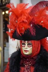 Beautiful woman in Venice at the annual Carnival , dressed in a tradition red costume and a mask , specific to the 18th Century 