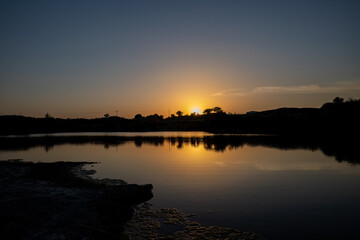 Beautiful sunset colours on the lake with tree silhouette.