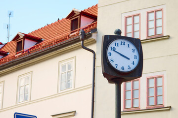 Fototapeta na wymiar Old street clock in Prague against the house with beautiful windows.