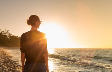 Thoughtful woman looking out to the ocean sunrise feeling happiness and freedom in nature. 