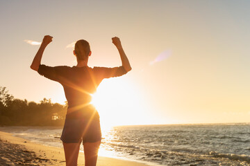 Young active strong fit woman living active healthy lifestyle flexing arms up to the sunrise. Health, fitness, vitality concept. 